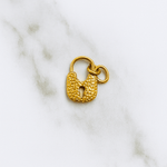 Gold padlock charm on a marble background