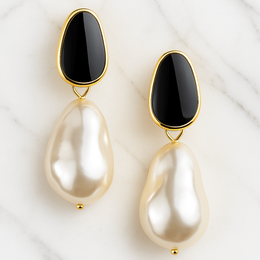 Pair of earrings with black stones and pearl-like drops on a white marble background