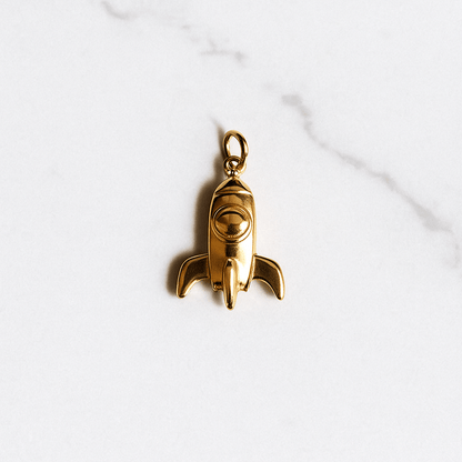Gold rocket-shaped pendant on a white marble surface