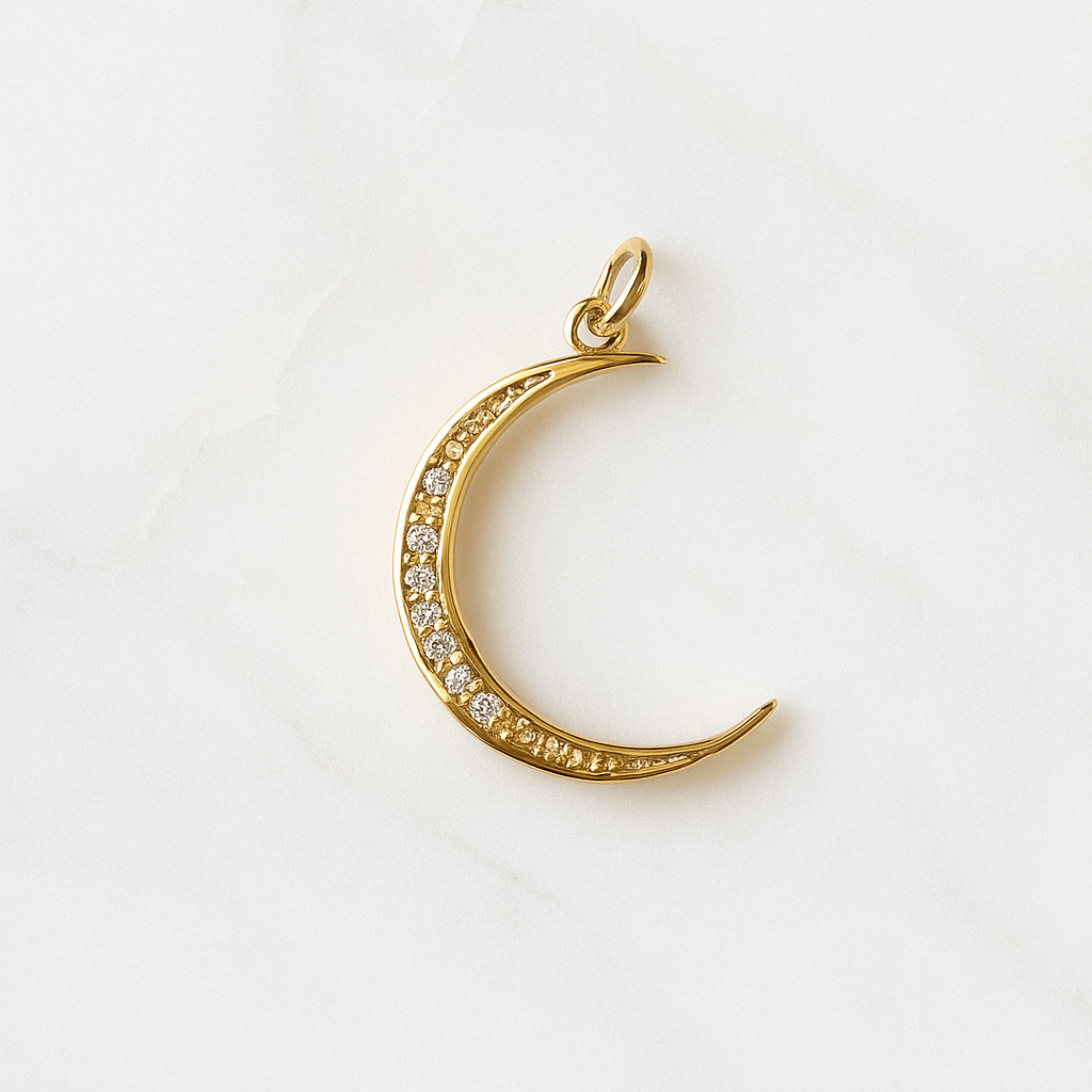 Gold moon-shaped pendant with embedded stones on a white background