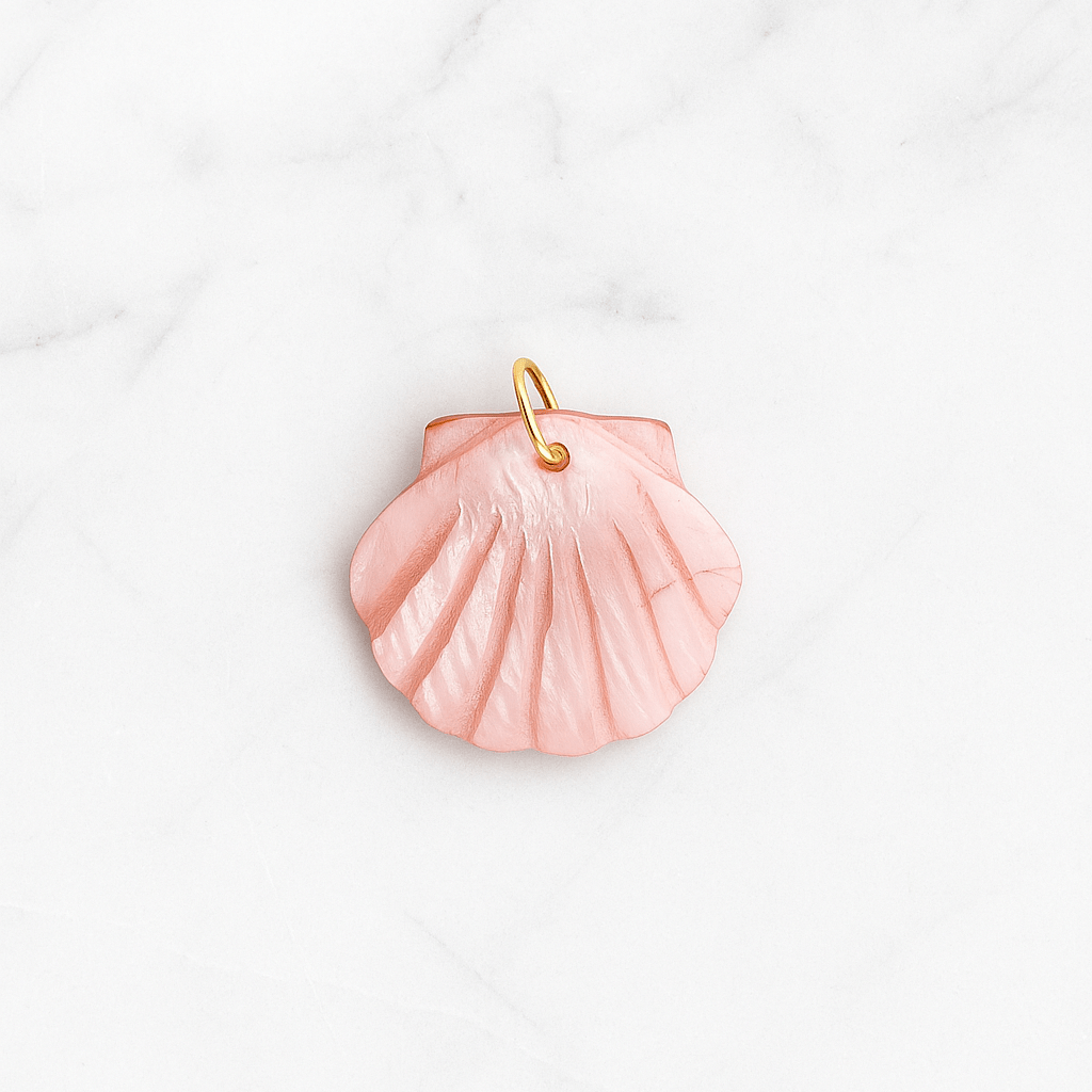 Pink shell pendant with gold chain on a white marble background