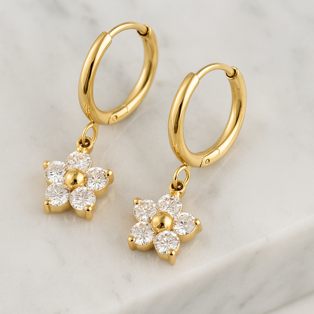 Gold hoop earrings with floral charms on a light background