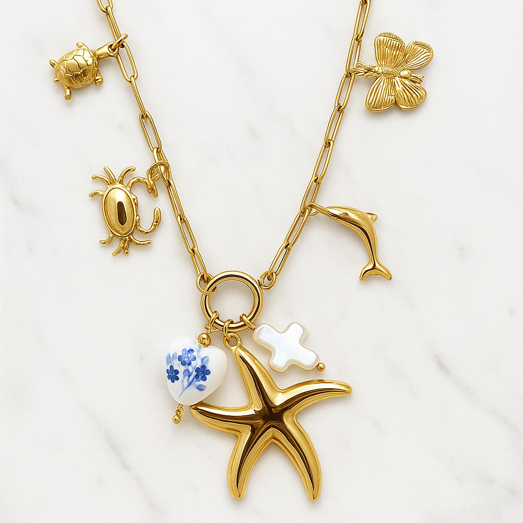 Gold necklace with starfish, blue gemstone, and other charms on a white background