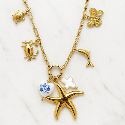 Gold necklace with starfish, blue gemstone, and other charms on a white background