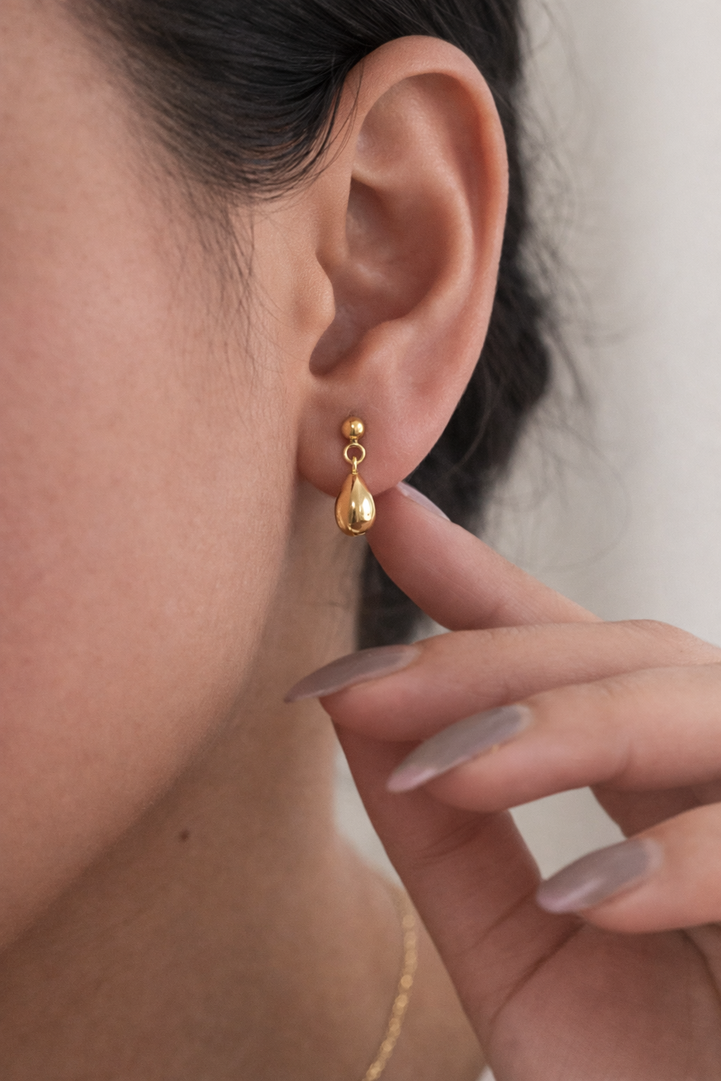 Gold earring worn by a person with a blurred background