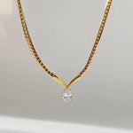 Gold necklace with a diamond pendant on a light gray background