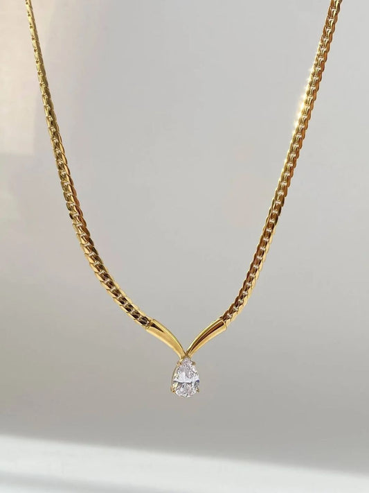 Gold necklace with a diamond pendant on a light gray background