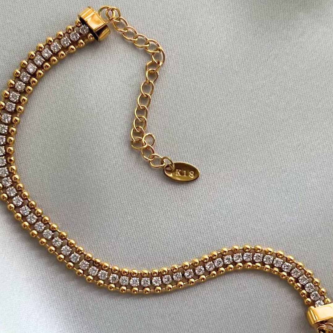 Gold bracelet with diamond accents on a light gray background