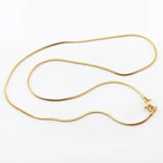 A gold-colored necklace with a simple chain design displayed against a white background.