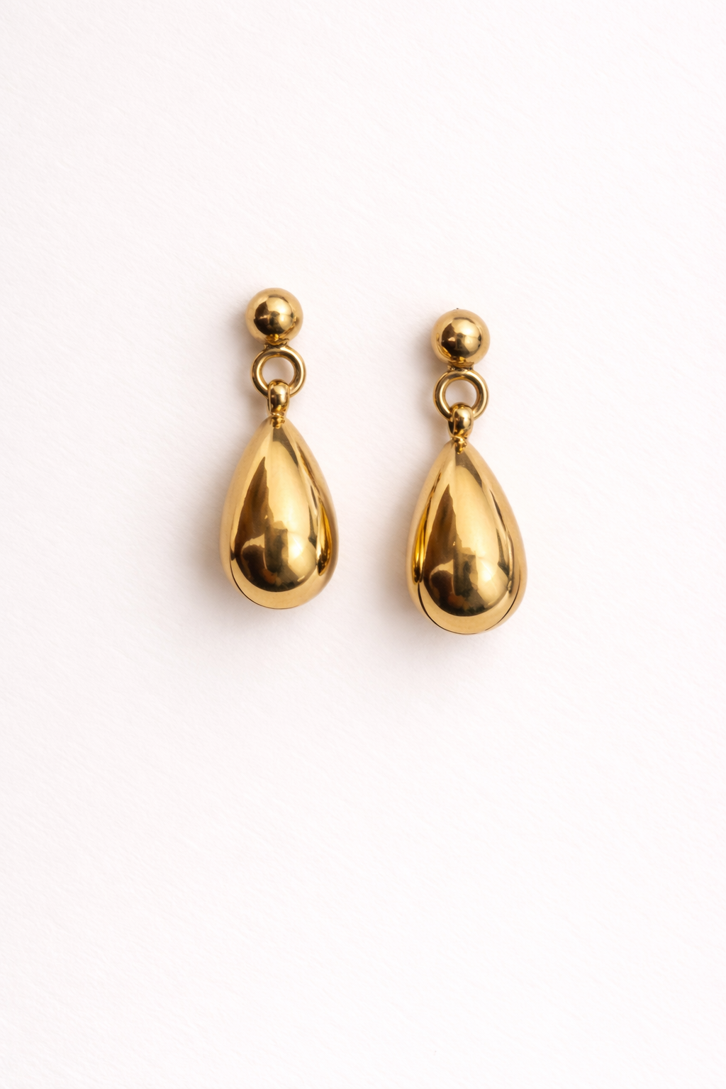 Gold teardrop earrings on a white background
