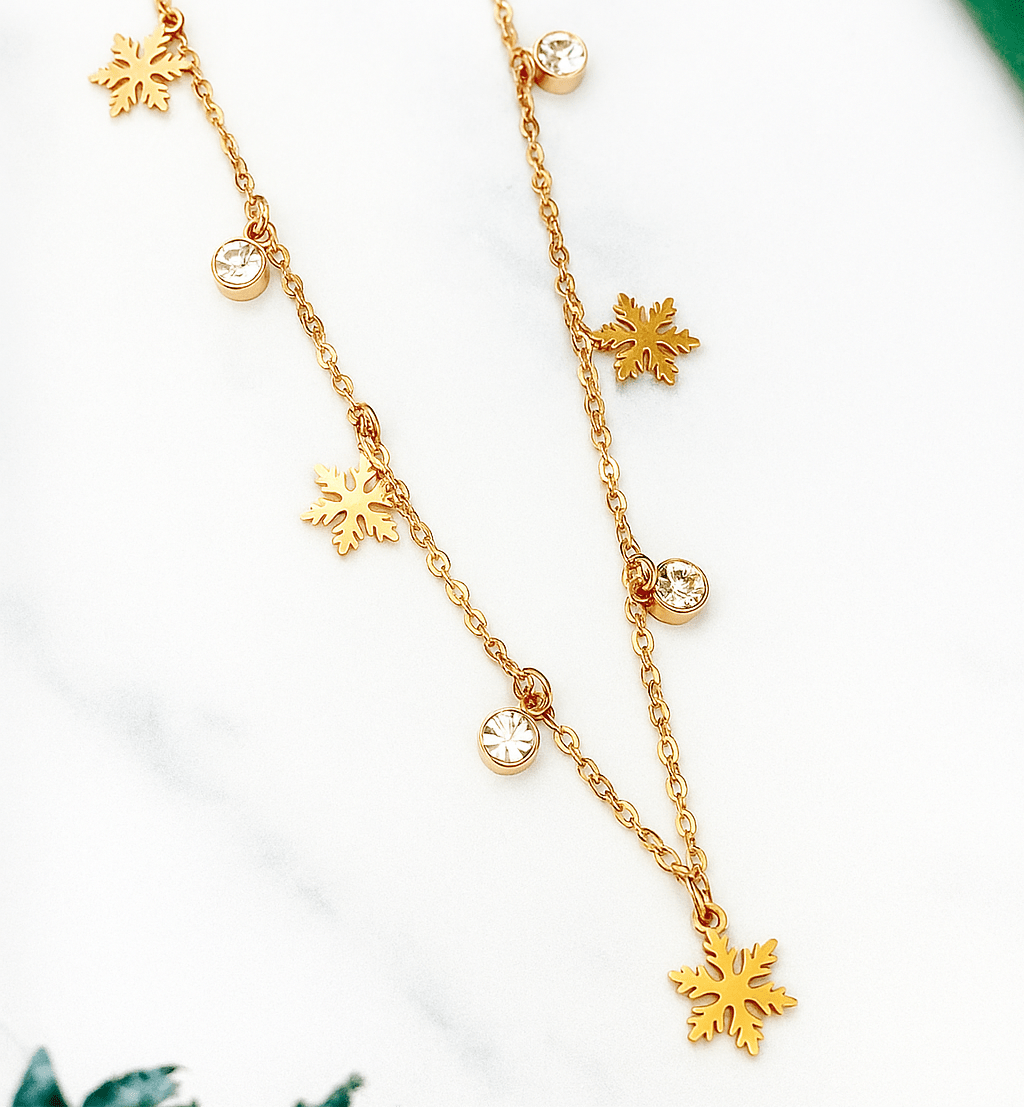Gold necklace with snowflake pendants on a white background