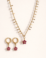 Gold necklace with red flower pendants on a white background