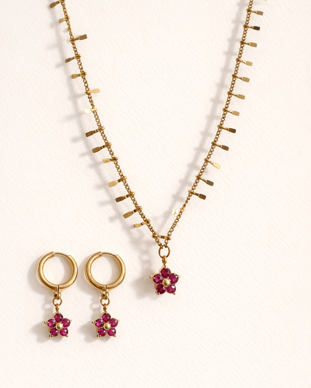 Gold necklace with red flower pendants on a white background