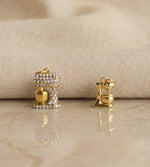 Gold earrings with gemstones on a beige fabric background