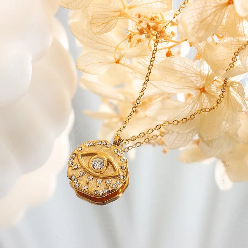 Gold necklace with a round pendant featuring a diamond, against a soft floral background.