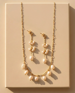 Pearl necklace and earrings set on a beige background