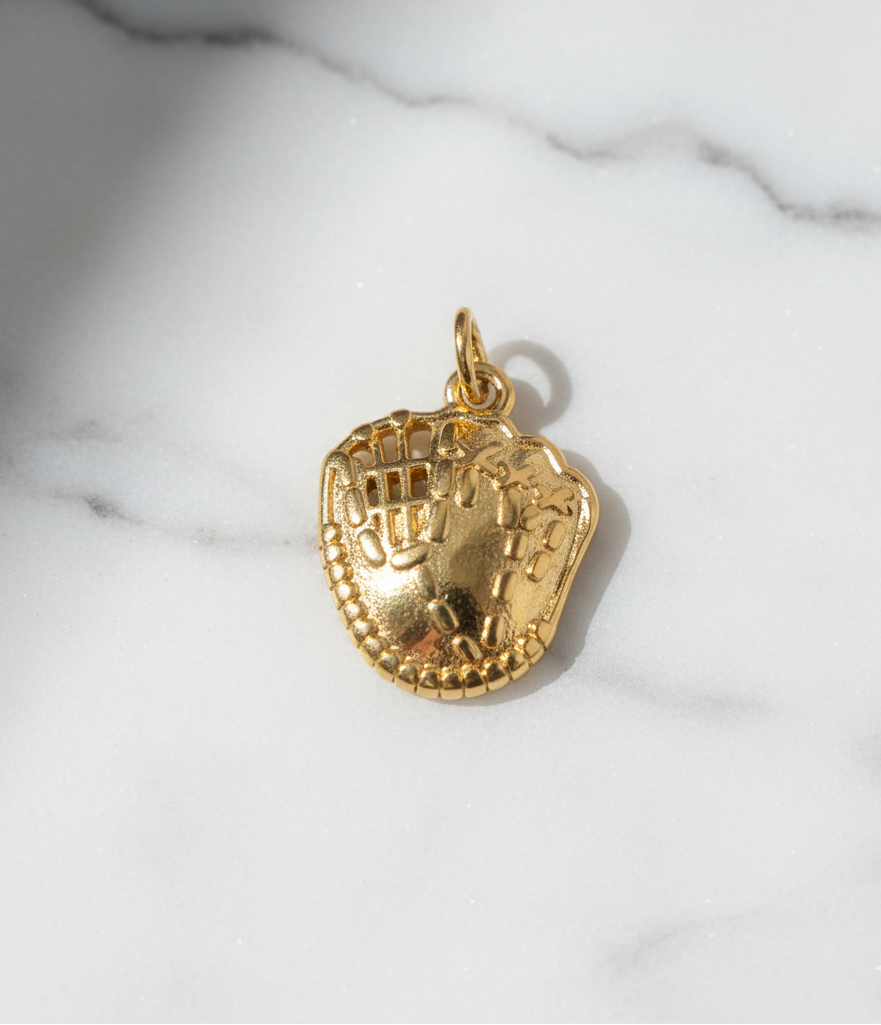 Gold baseball glove charm on a marble surface
