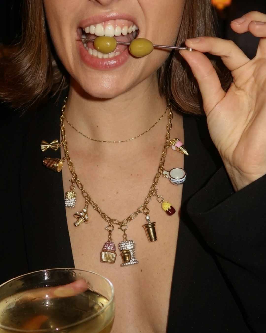 Person eating olives with a cocktail in the background