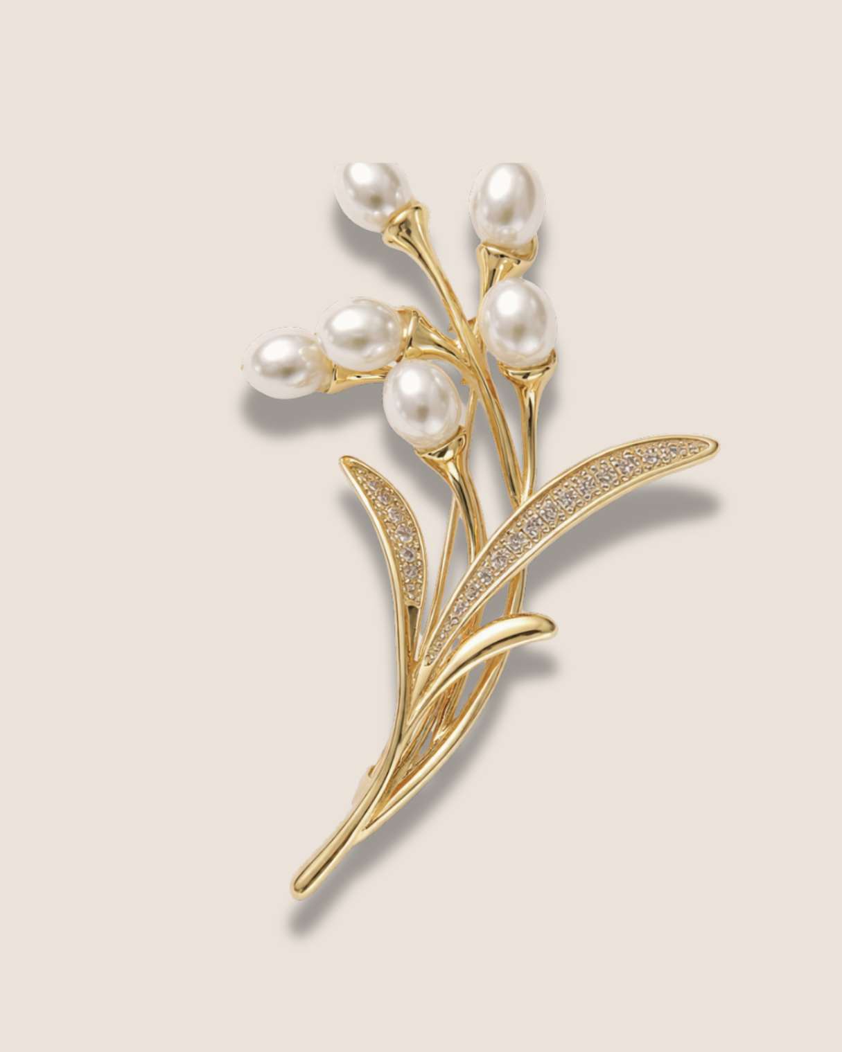 Gold brooch with pearls on a beige background