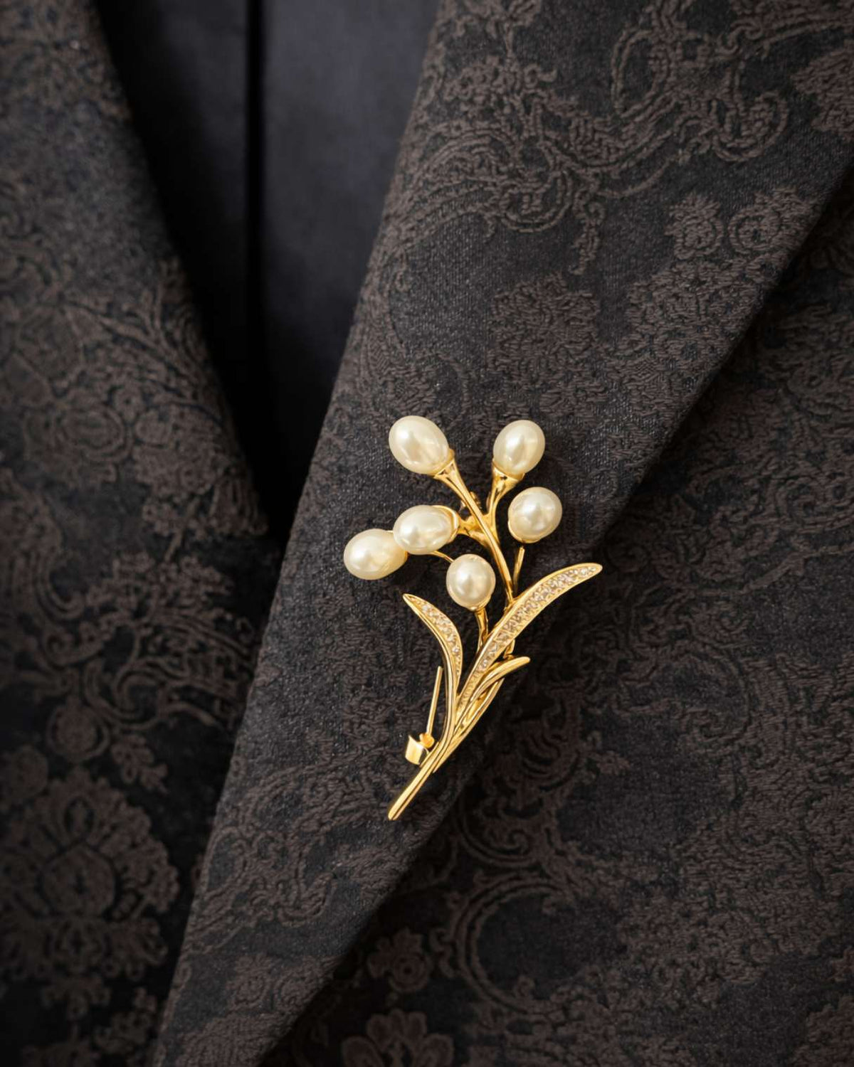 Gold brooch with pearls on a black textured fabric background