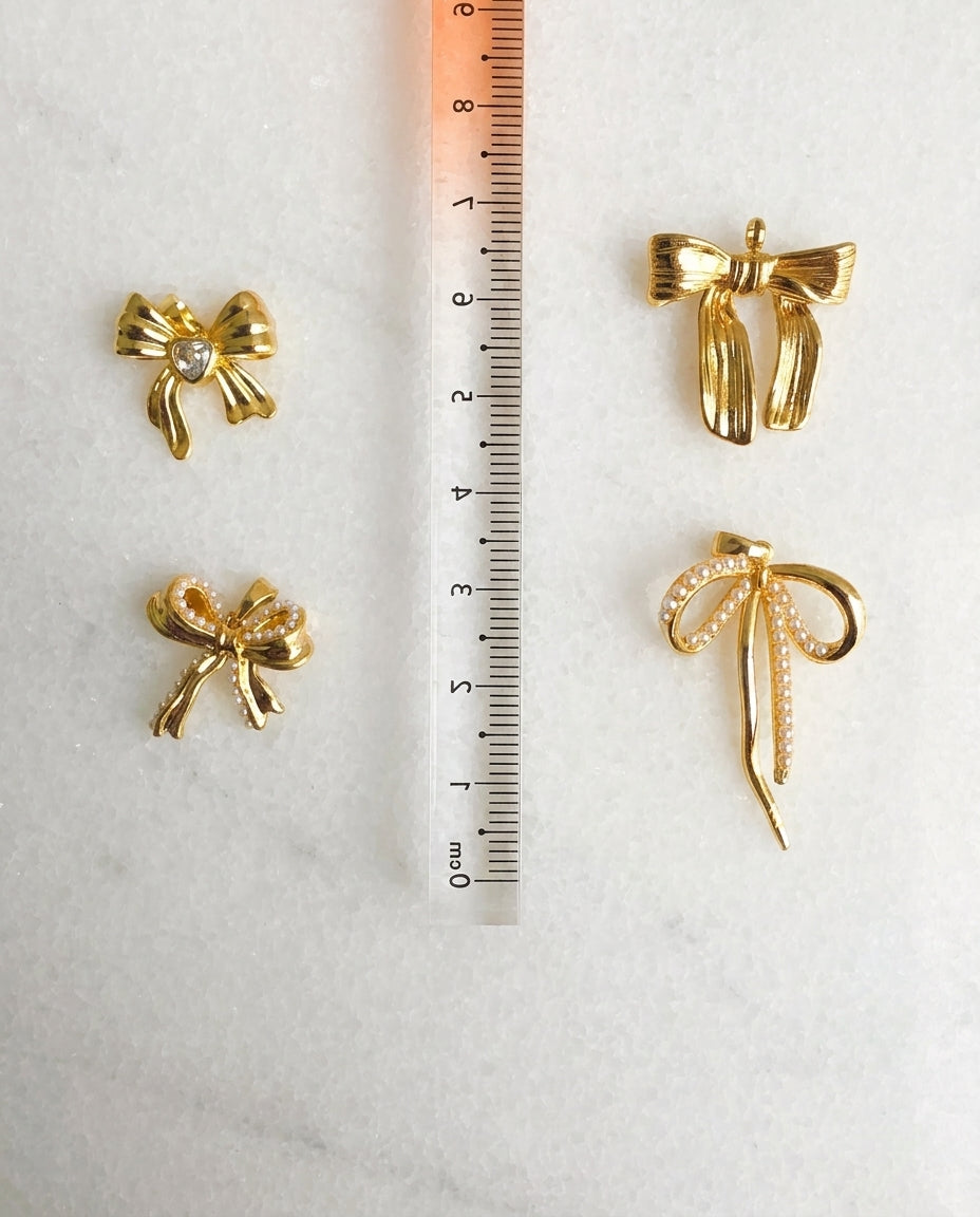 Gold bow-shaped earrings with a ruler for scale on a white background