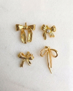 Set of gold bow-shaped earrings on a light background