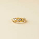 Gold ring with small diamonds on a beige cushion against a light gray background