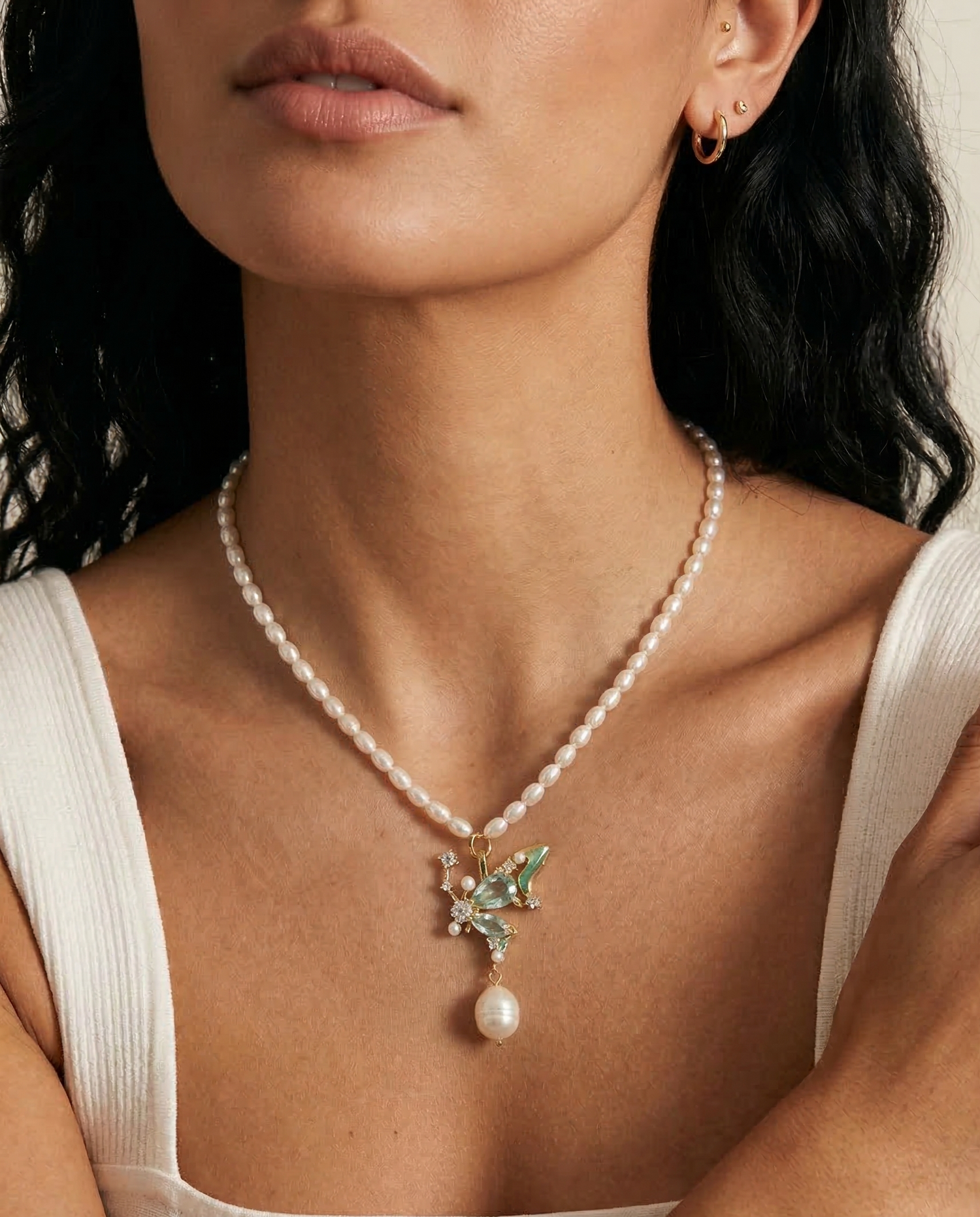 Close-up of a woman wearing a pearl necklace with a pendant.