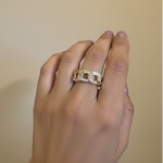 Hand wearing a gold ring with crystals on a beige background