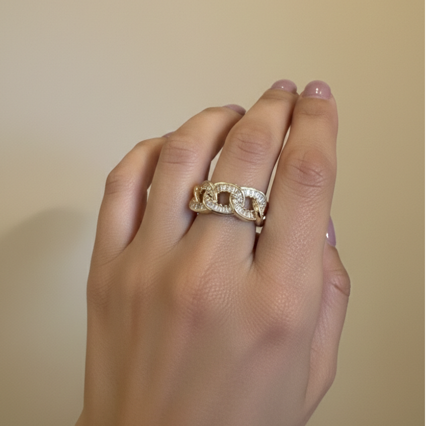 Hand wearing a gold ring with crystals on a beige background