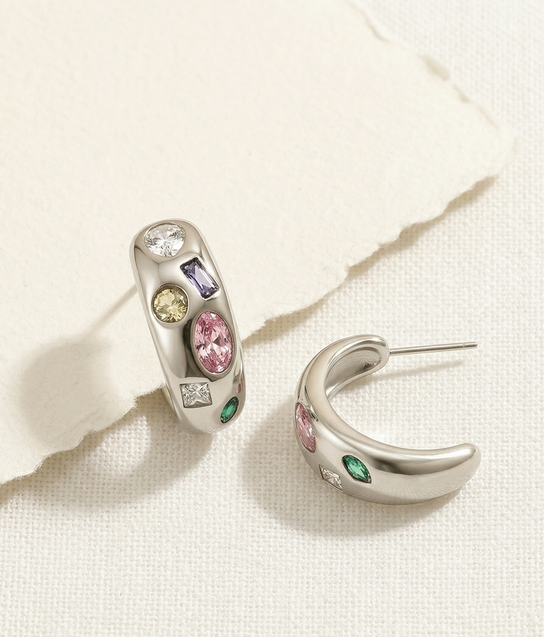 Pair of silver hoop earrings with colorful gemstones on a light background