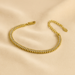 Gold bracelet with clear stones on a beige background