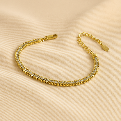 Gold bracelet with clear stones on a beige background