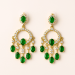 Gold earrings with green gemstones on a beige background