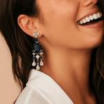 Close-up of a woman wearing a pair of blue gemstone earrings.