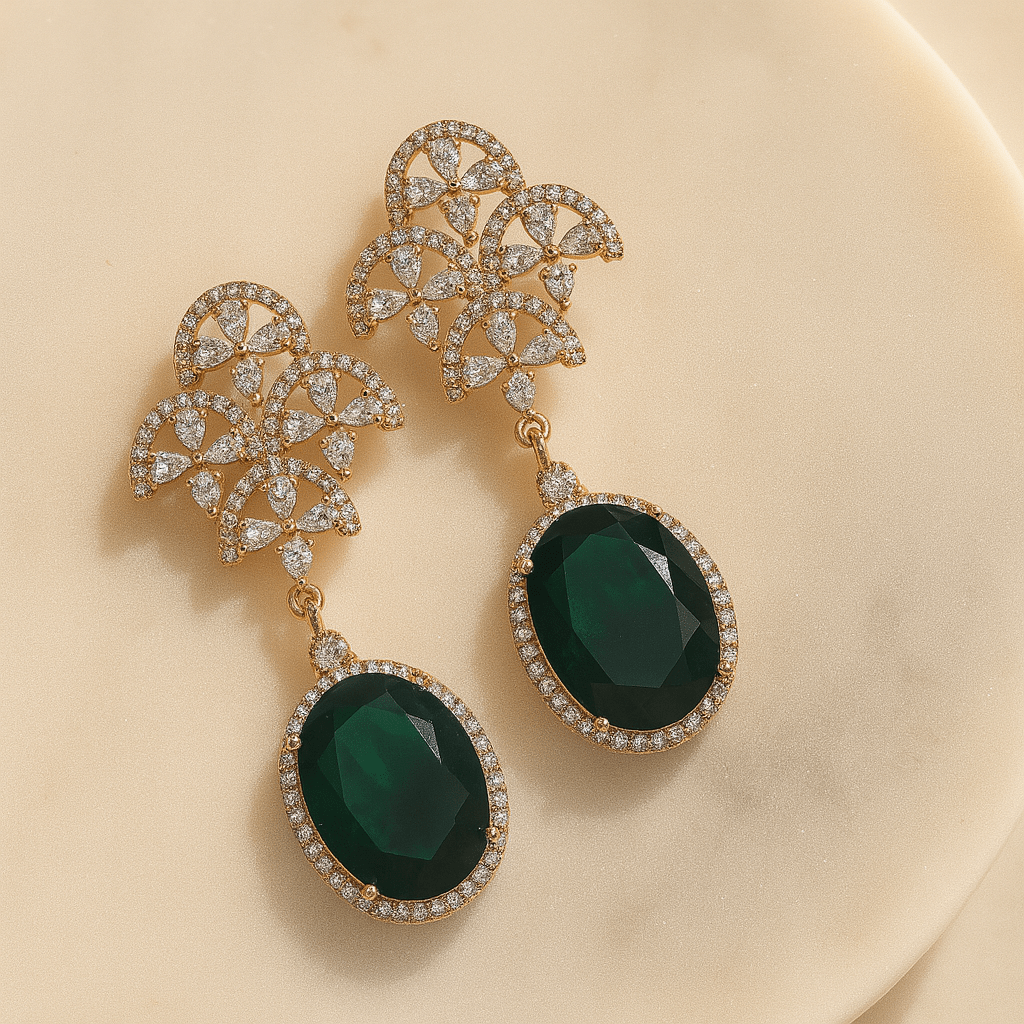 Pair of gold earrings with green gemstones on a beige background