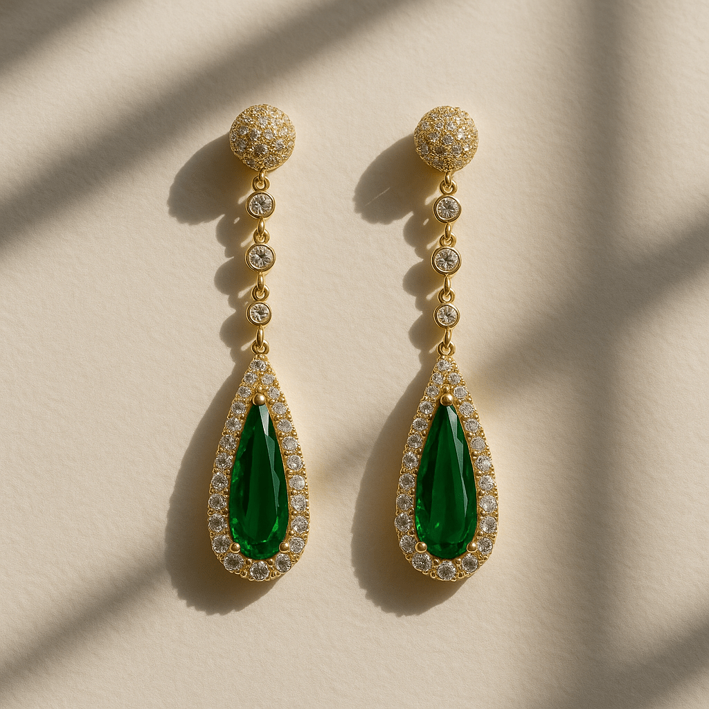 Gold earrings with green teardrop stones on a beige background