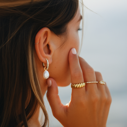 Close-up of a woman wearing gold earrings, ring, and bracelet with a blurred background