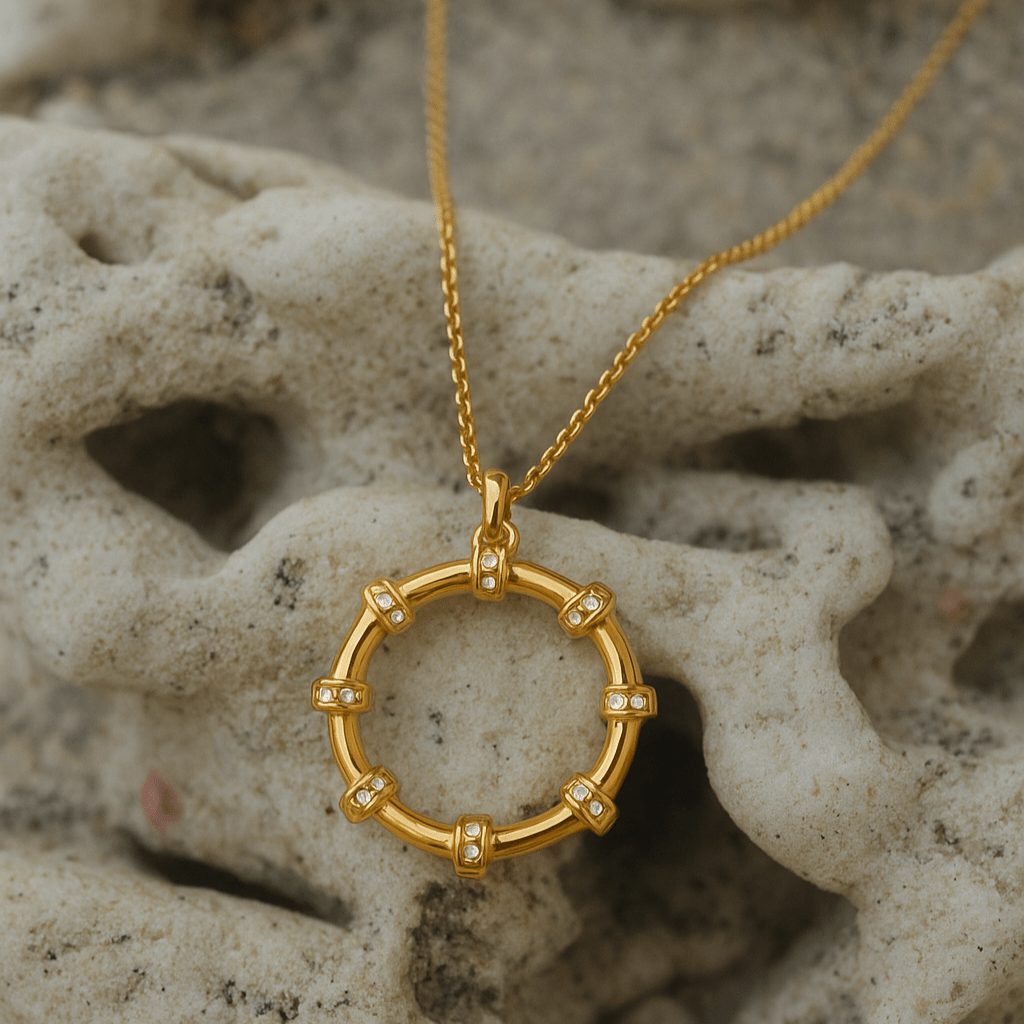 Gold necklace with a circular pendant on a textured stone surface