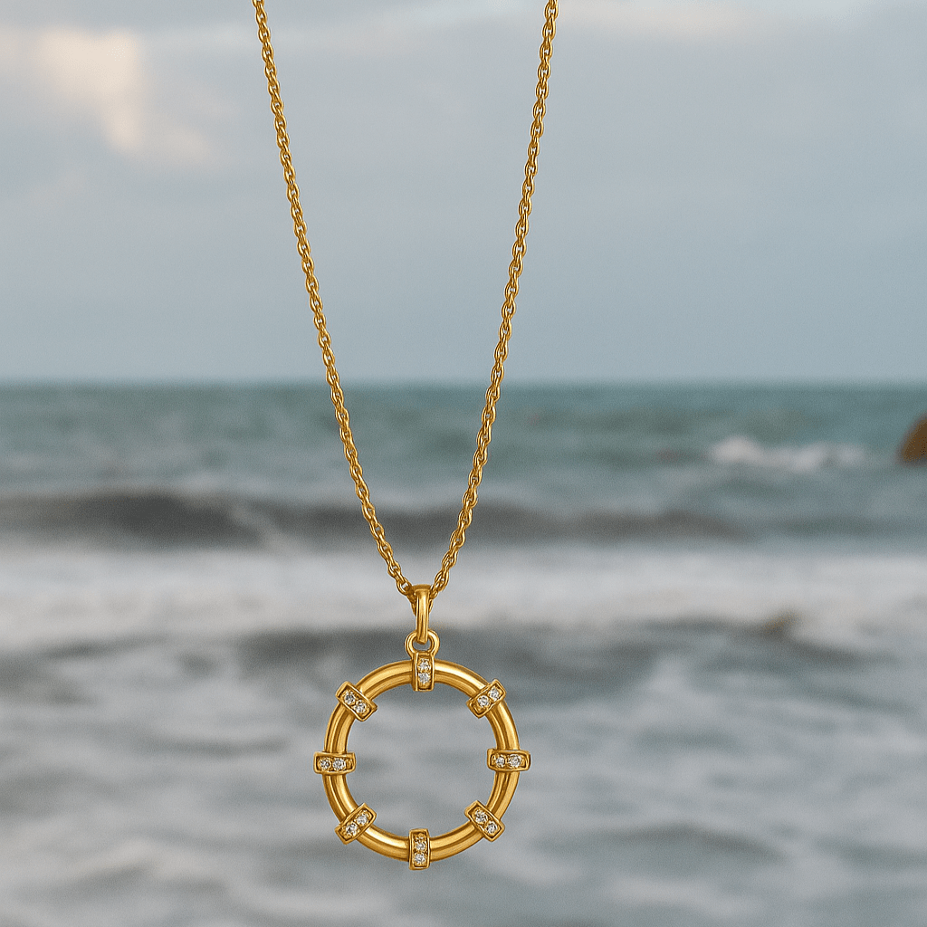 Gold necklace with a circular pendant over a blurred ocean background
