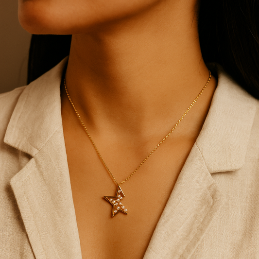 Gold necklace with a star pendant worn by a person in a beige blazer.