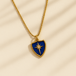 Gold necklace with a blue heart-shaped pendant featuring a star design on a beige background