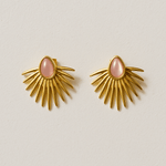 Gold sunburst earrings with pink centers on a beige background