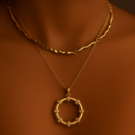Gold necklace with a circular pendant on a person against a dark background