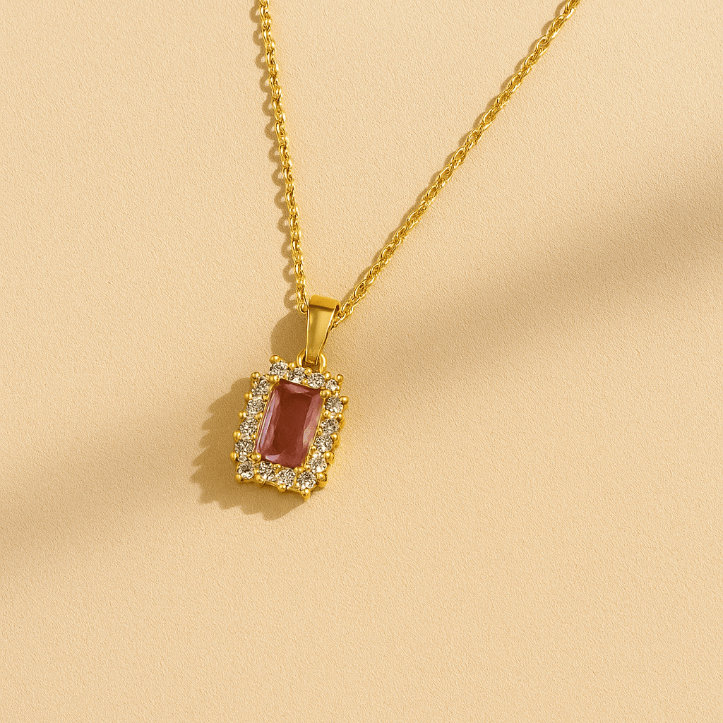 Gold necklace with a red gemstone pendant on a beige background