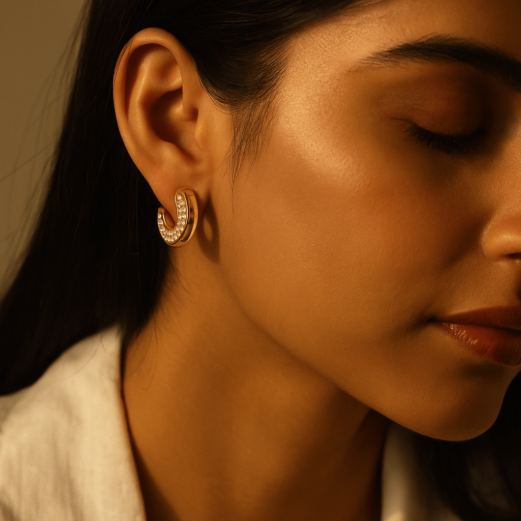 Close-up of a woman wearing gold hoop earrings with a warm, soft focus.