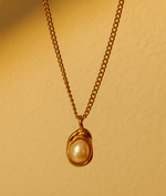 Gold necklace with a pearl pendant on a beige background