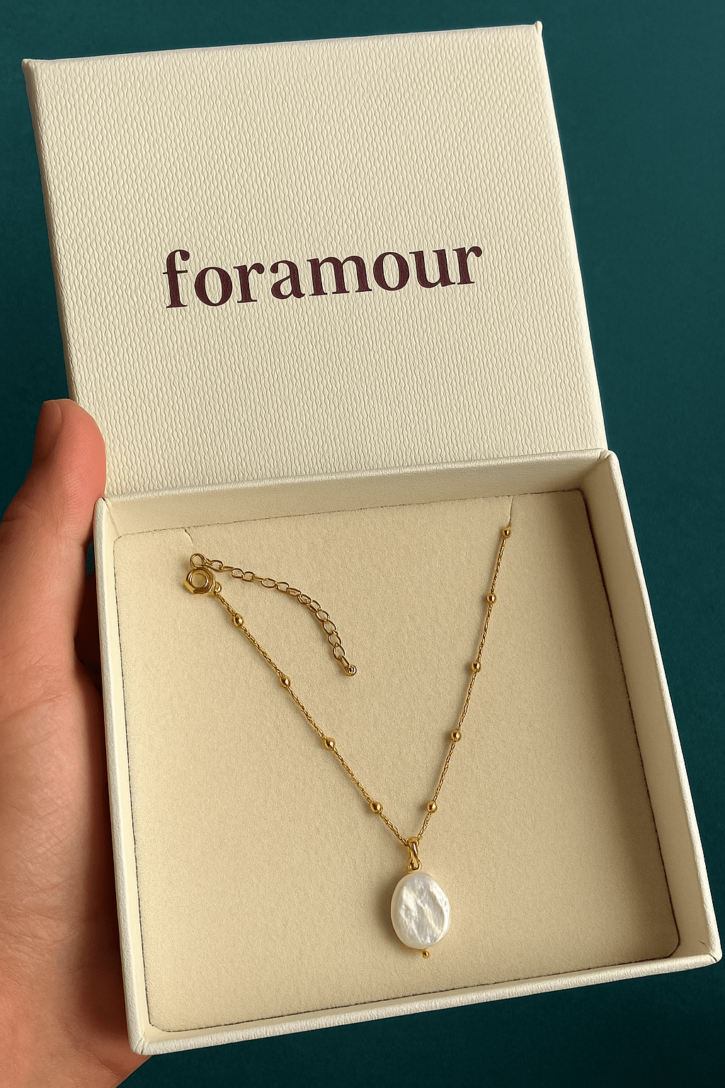 A gold chain necklace with a baroque pearl pendant, presented in a branded box with the text 'foramour'.