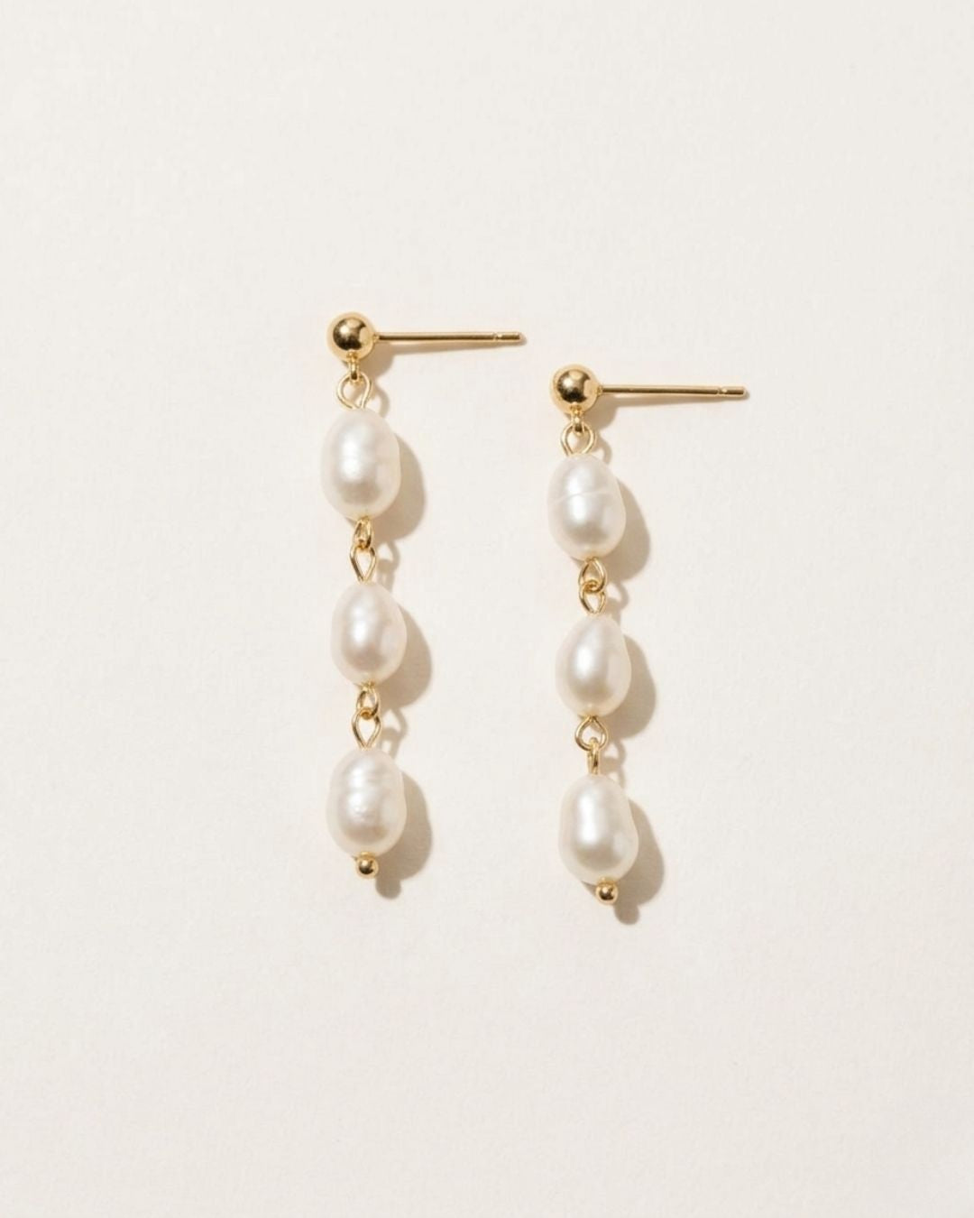 Pair of pearl earrings on a light beige background