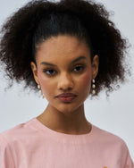 Woman with styled hair wearing a pink top against a neutral background